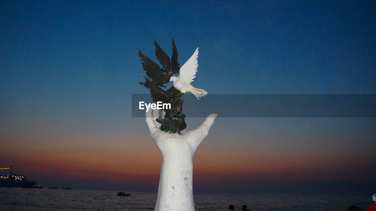 Hand of peace monument on shore against sky