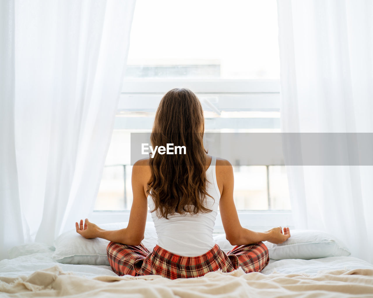 Back view of woman yoga pose in bed after wake up, entering new day happy and relaxing