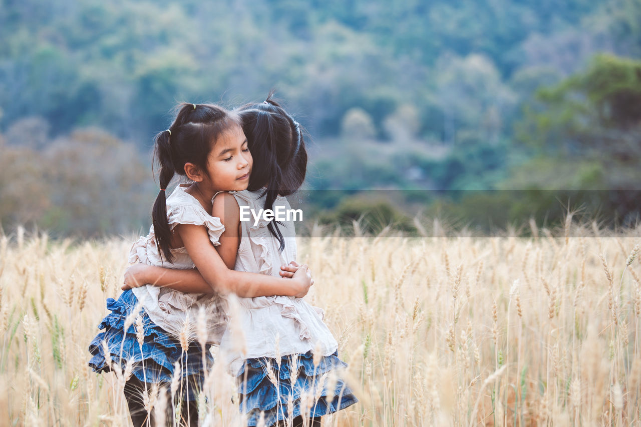 Girl embracing sister on agricultural field