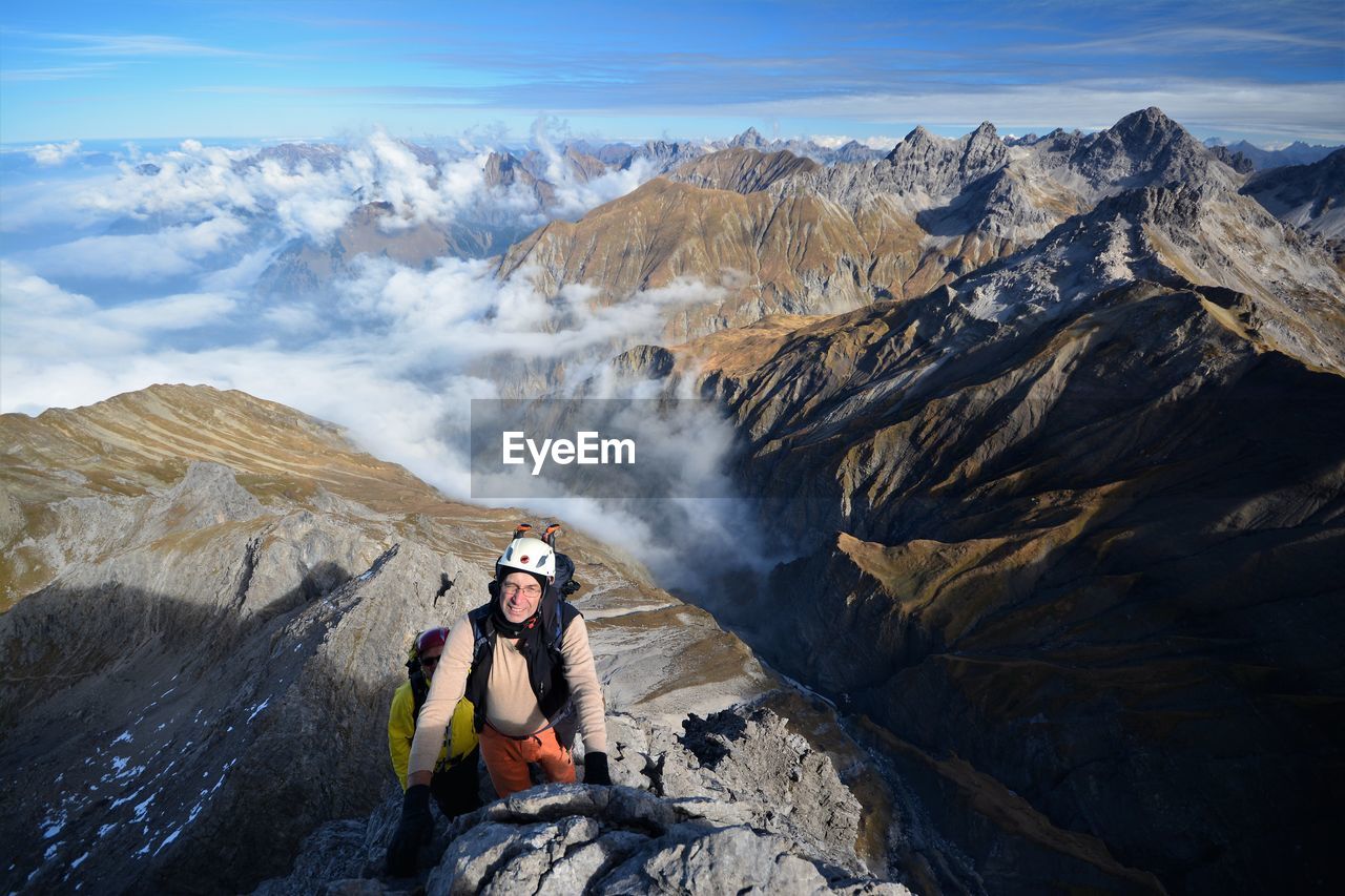 Portrait of senior man standing on mountain against sky