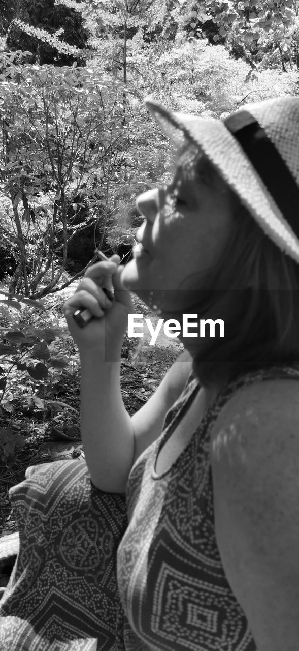 SIDE VIEW OF WOMAN LOOKING AWAY WHILE HOLDING PLANTS