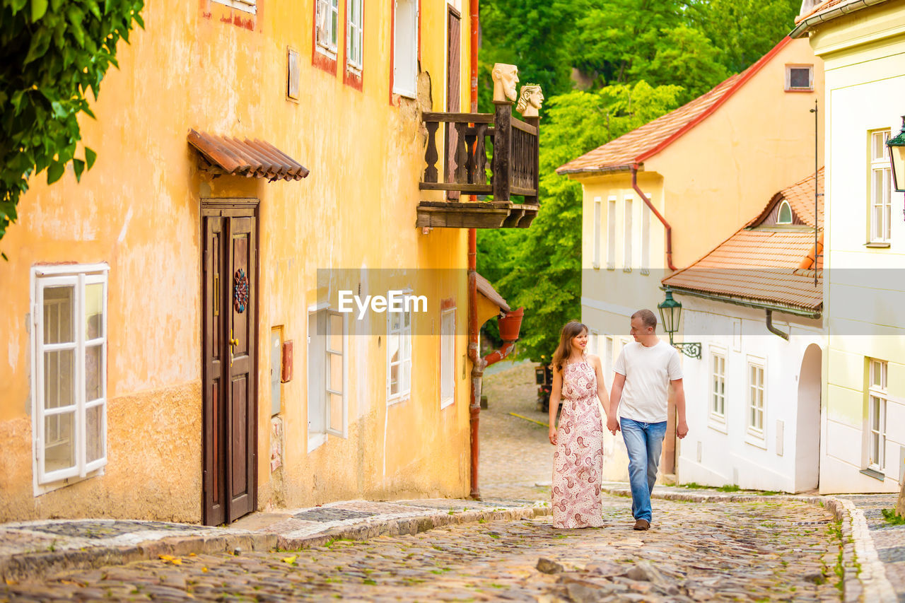 REAR VIEW OF COUPLE STANDING OUTSIDE HOUSE