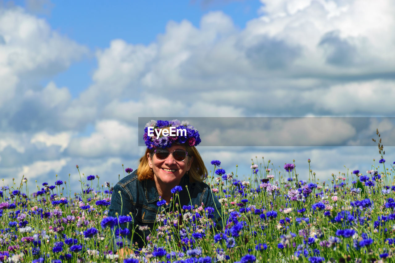 A woman in the middle of a colorful field of cornflowers is happy about summer