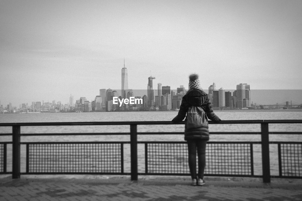 FULL LENGTH REAR VIEW OF WOMAN STANDING ON BRIDGE