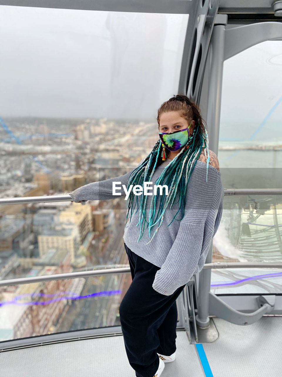 Woman looking at camera while standing against railing