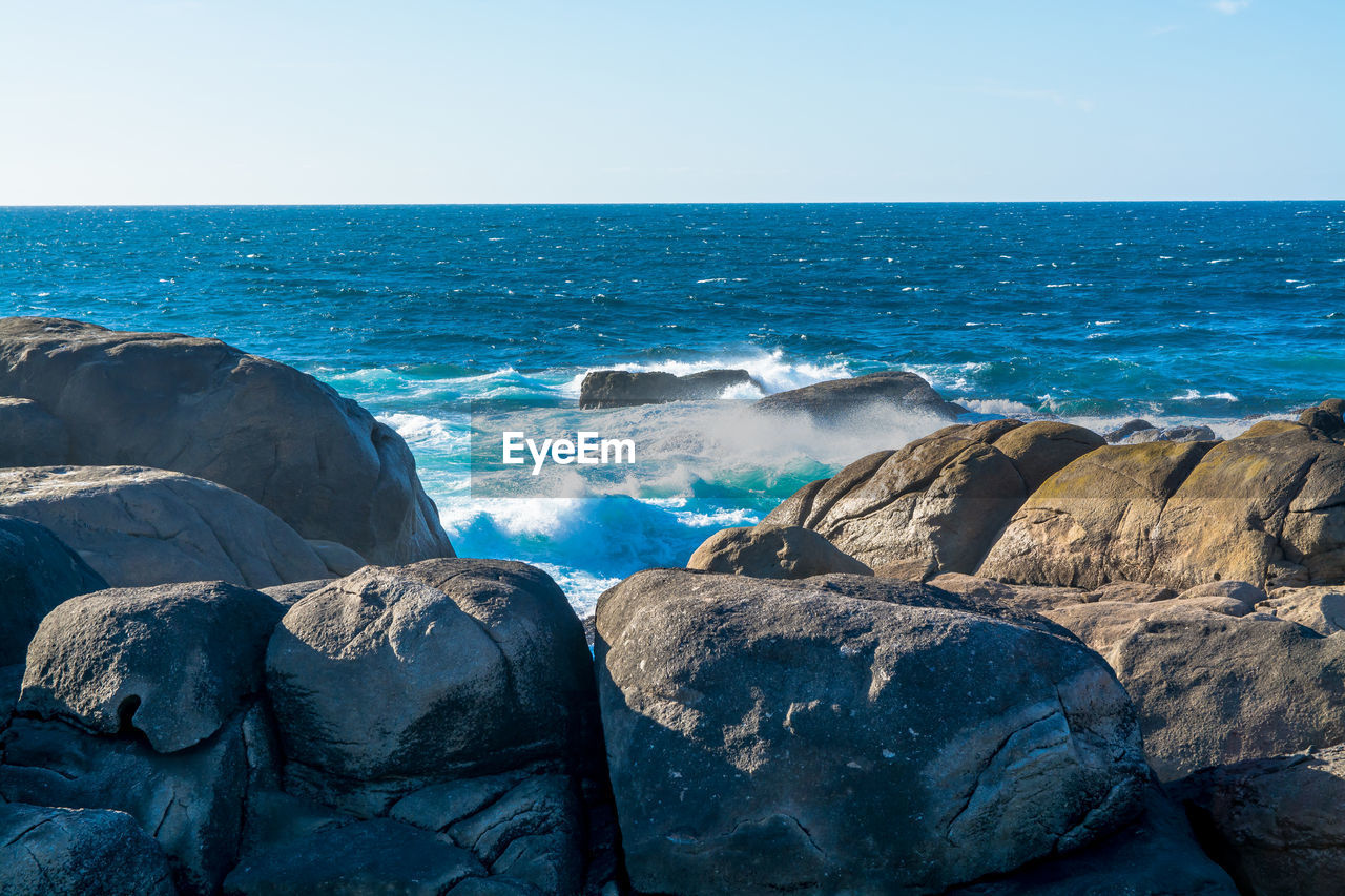 Eroded boulders against wavy sea