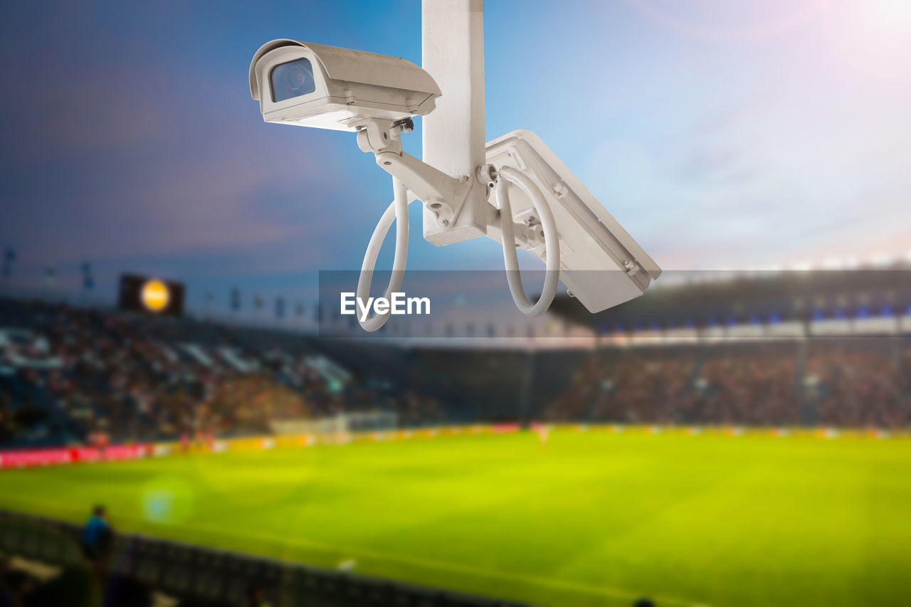 Close-up of security camera at soccer field against sky