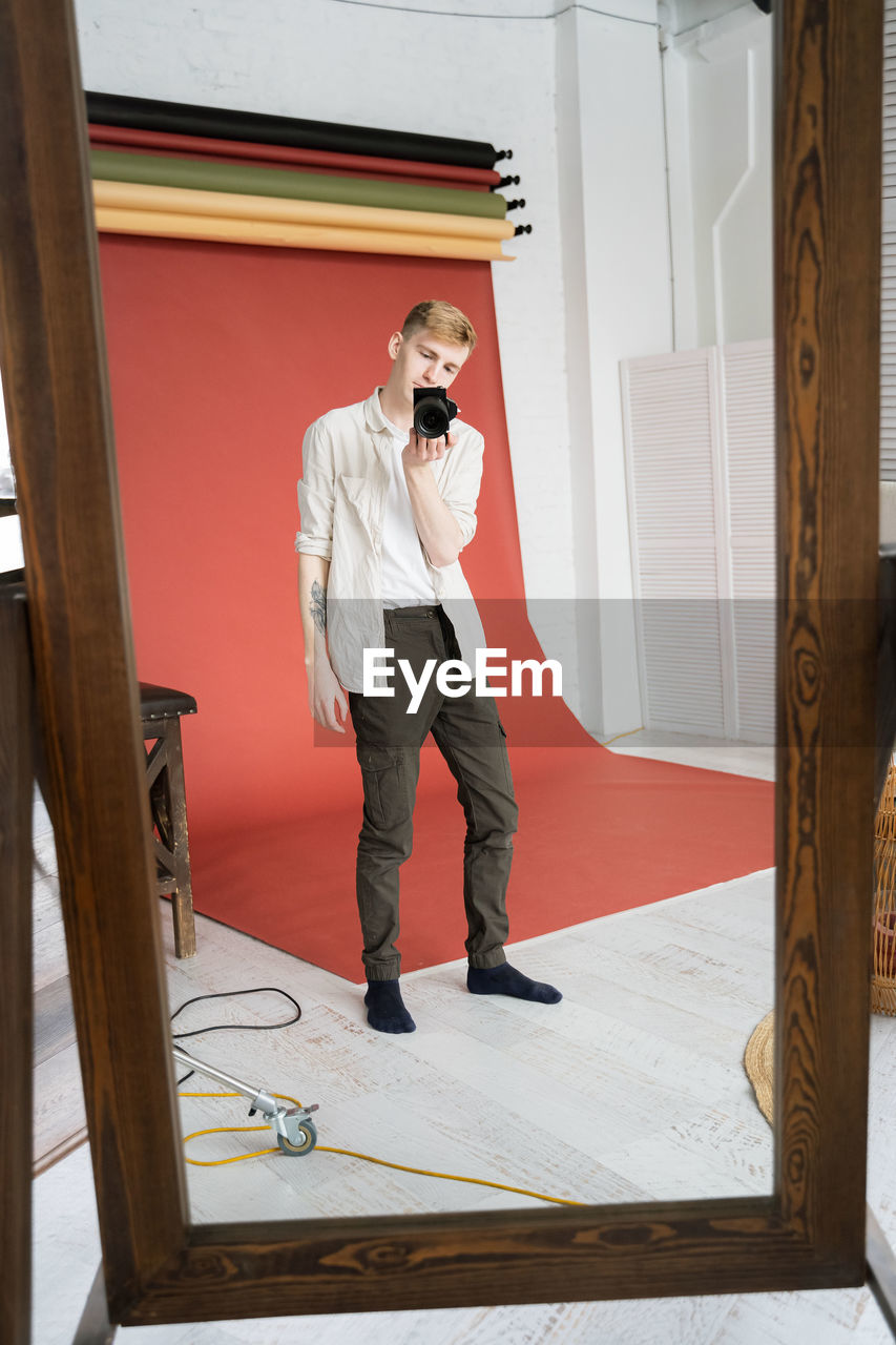 FULL LENGTH OF MAN USING PHONE WHILE STANDING AT ENTRANCE