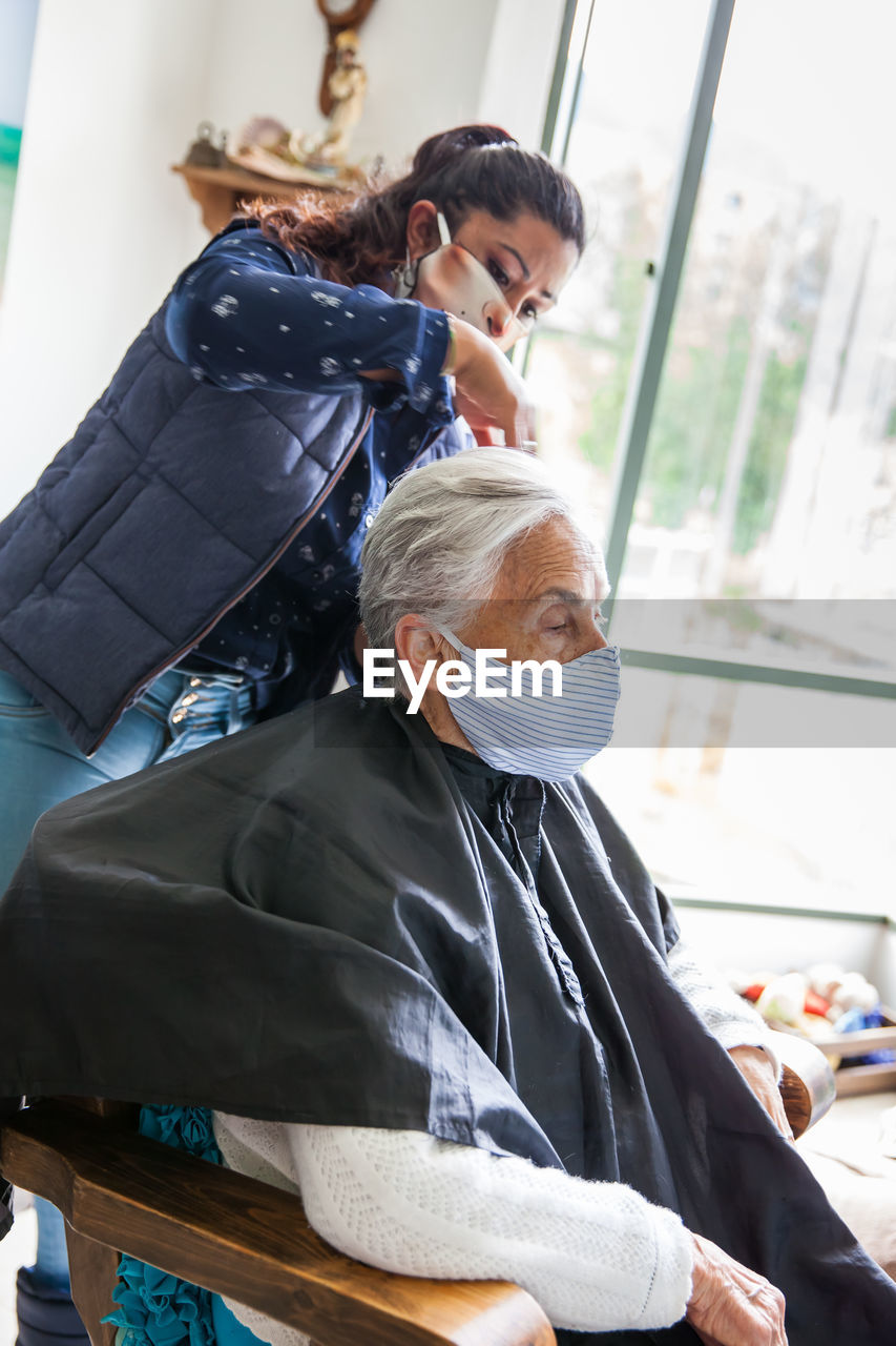 Beautician treating hair of customer at home