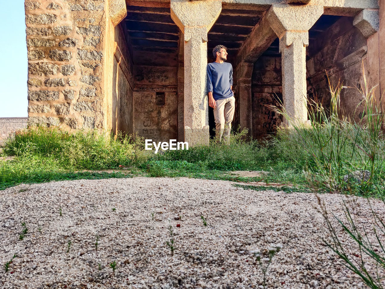 Portrait of man standing by tree against building