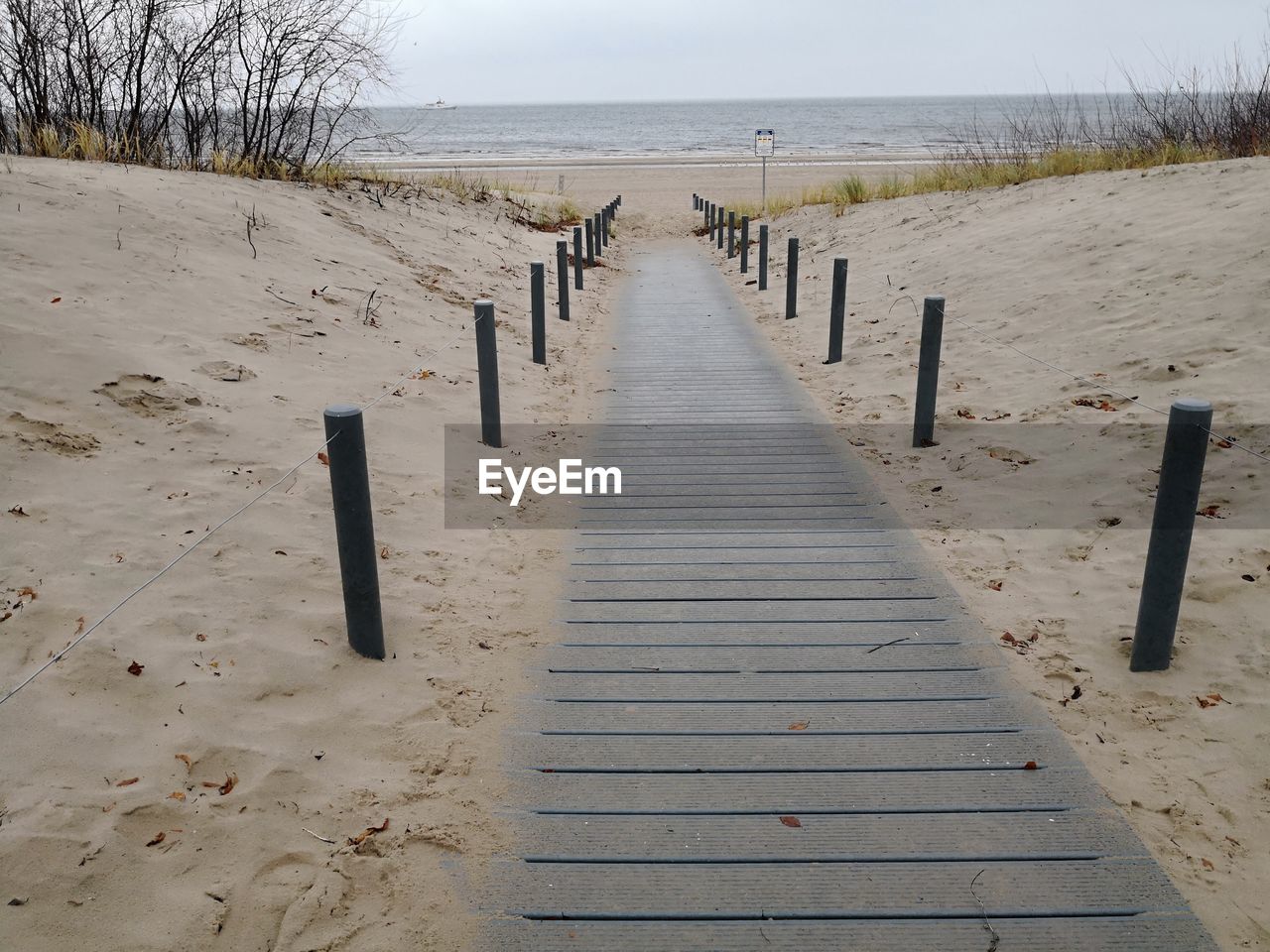 WOODEN POSTS AT BEACH AGAINST SKY