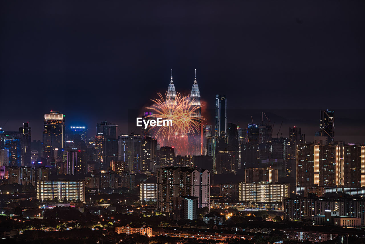 FIREWORK DISPLAY OVER ILLUMINATED BUILDINGS IN CITY