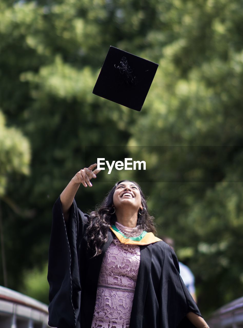 Smiling young woman throwing mortarboard 