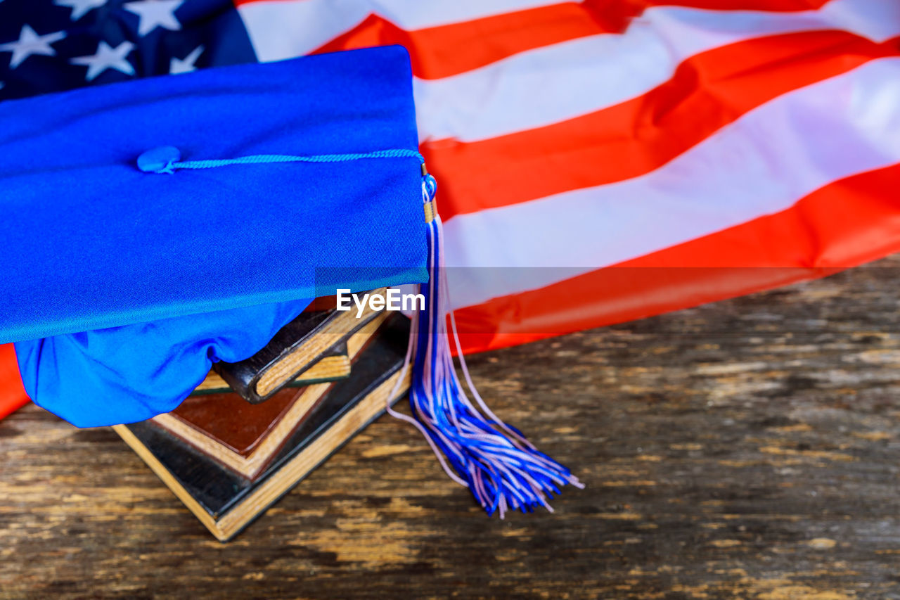 Close-up of mortarboard with books on american flag at table