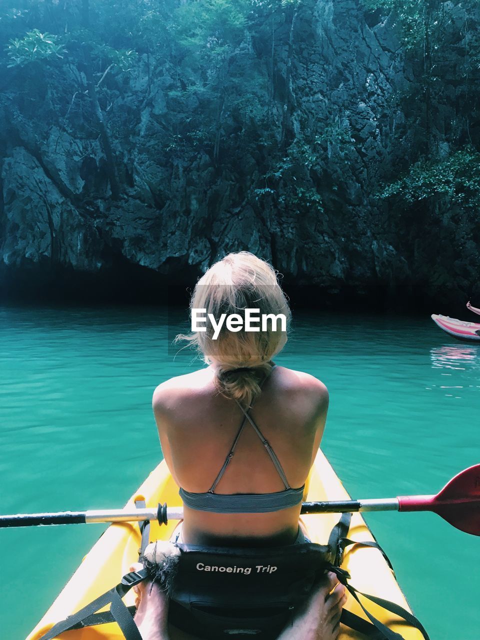 Rear view of woman kayaking in sea against mountain