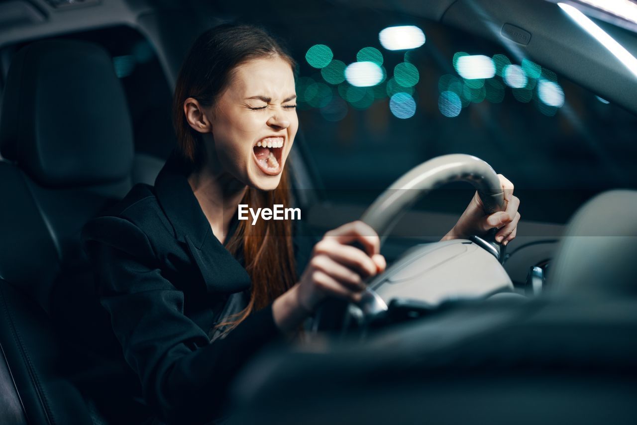 Young woman screaming while sitting in car