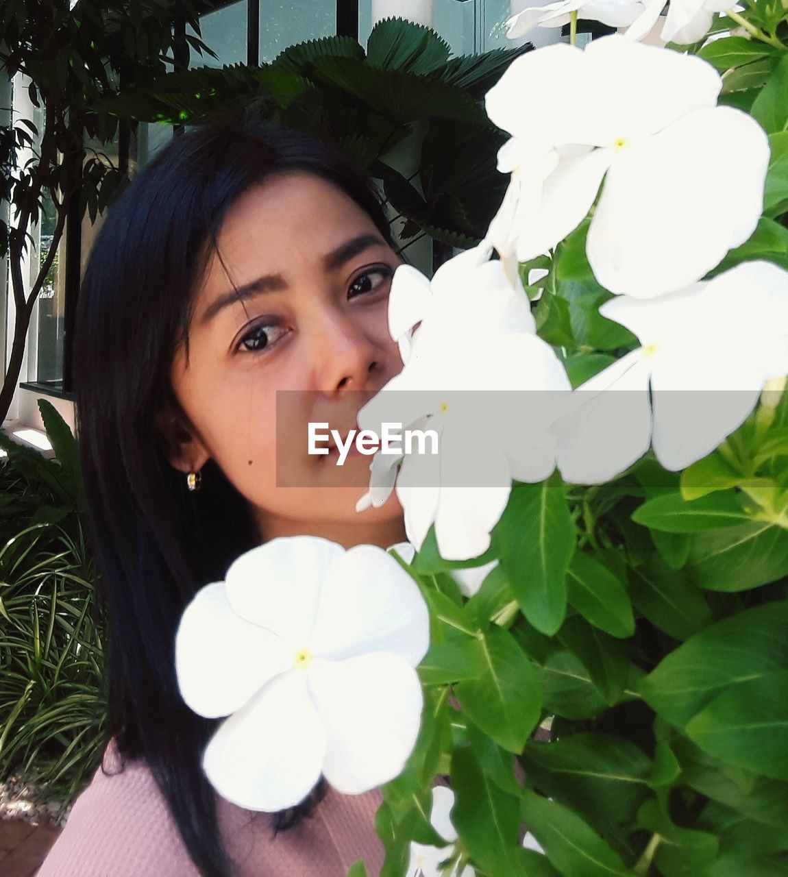 Portrait of beautiful woman against by flowering plants