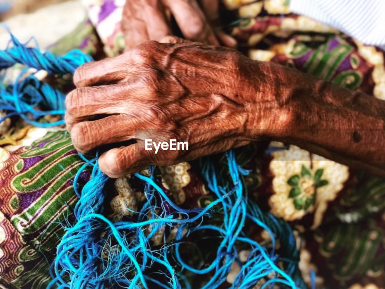 Midsection of senior woman holding threads