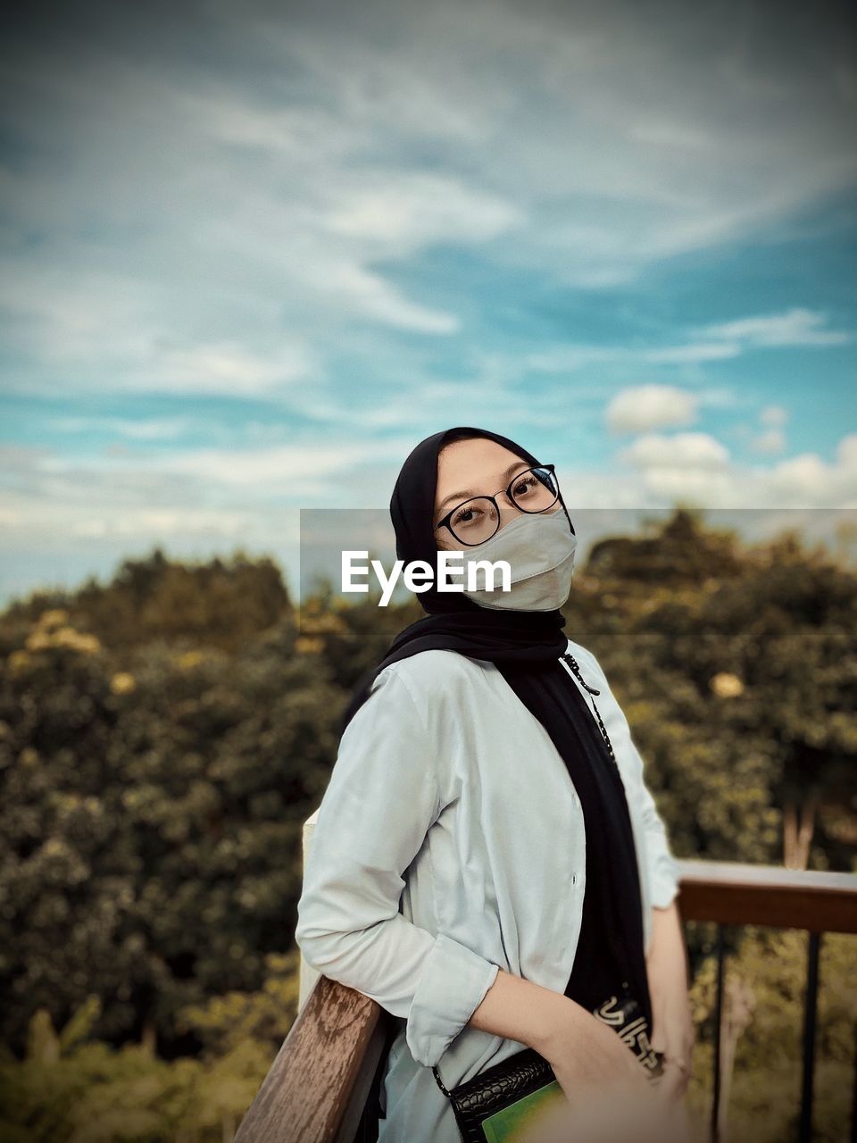 Portrait of woman wearing mask standing against sky