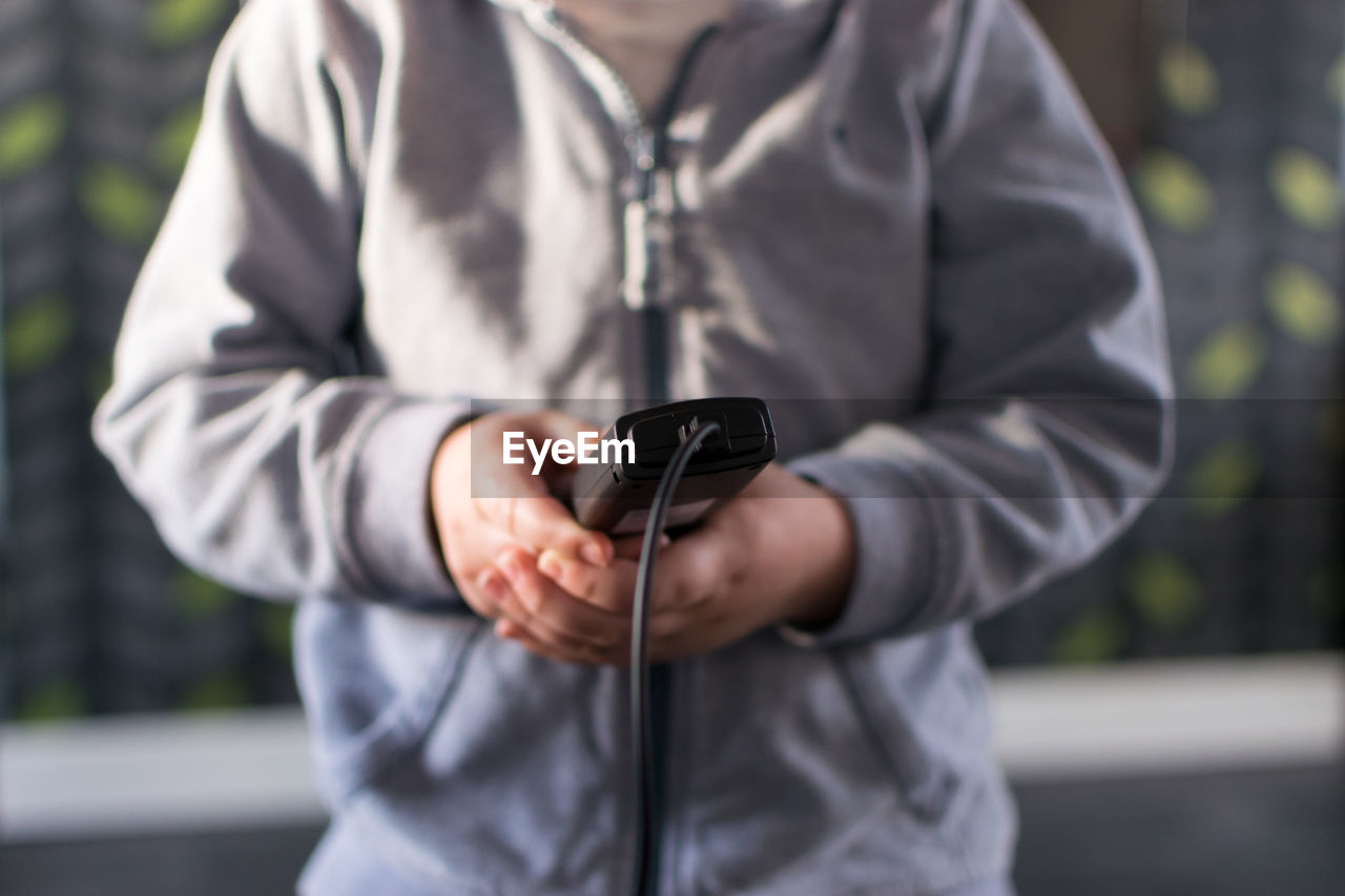 Midsection of boy holding remote control