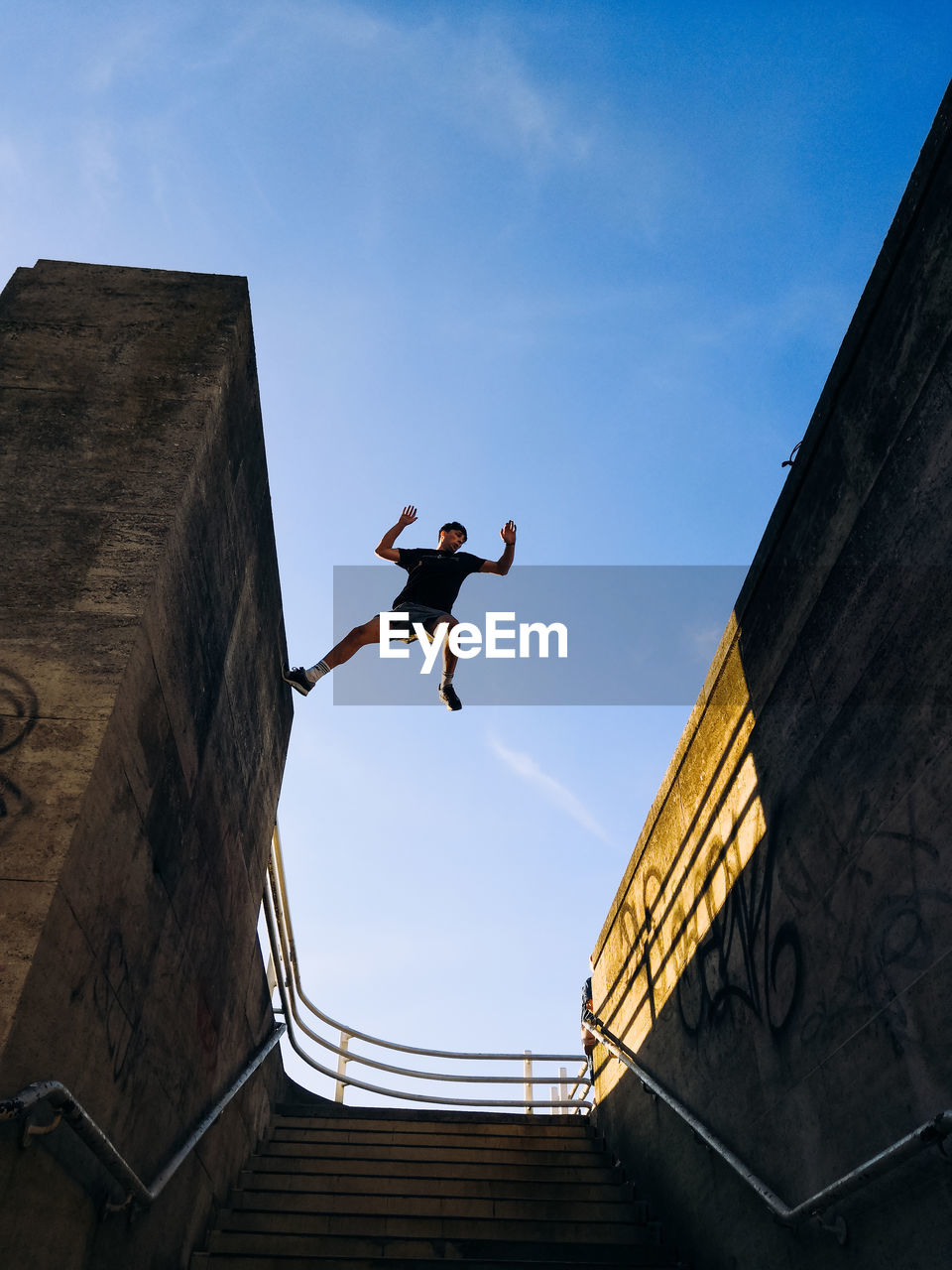 Low angle view of man jumping against sky