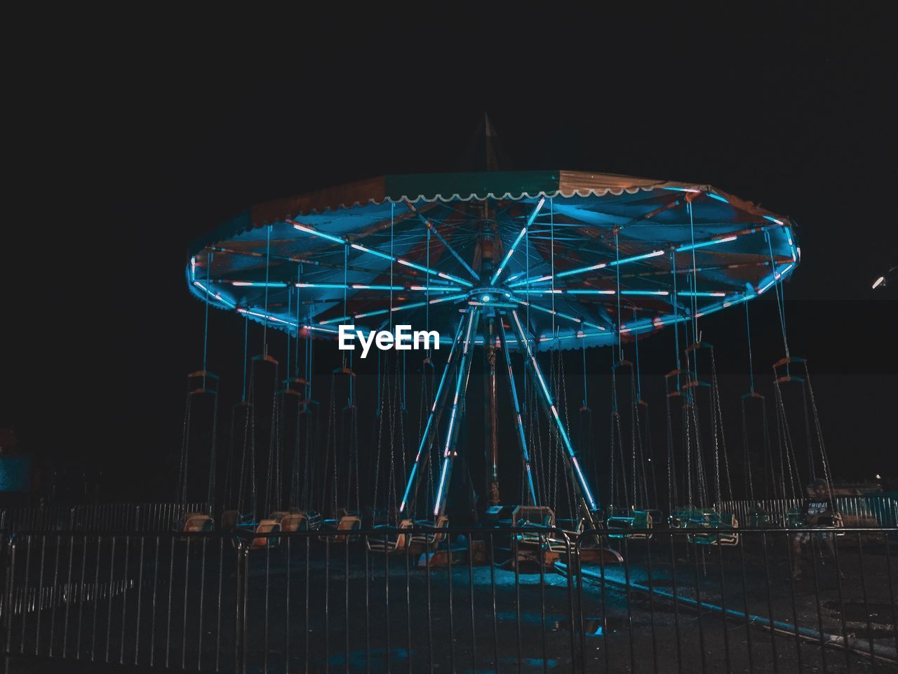 Illuminated carousel against sky at night