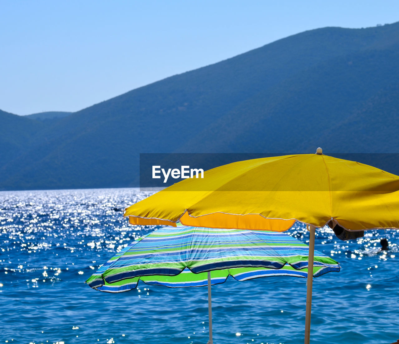 Yellow umbrella on beach against clear blue sky