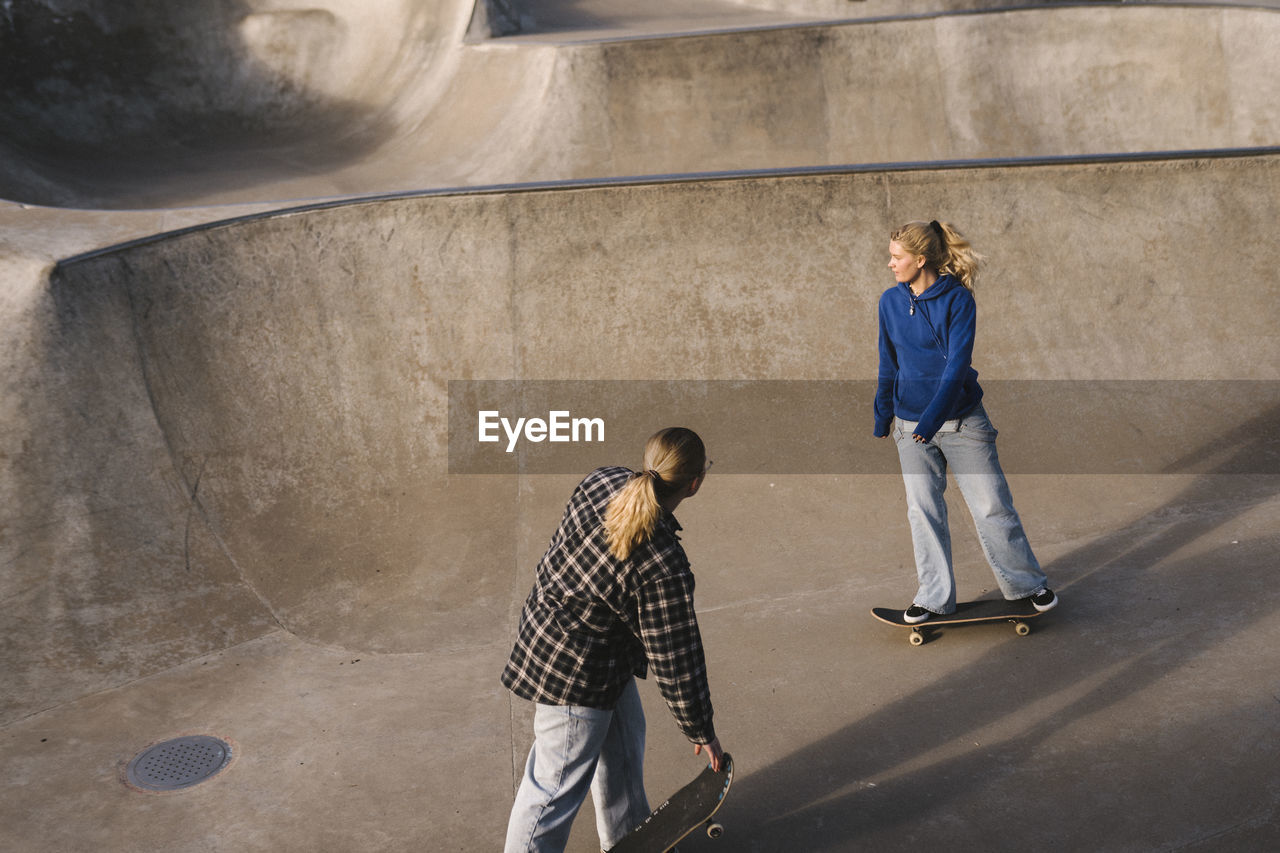 Teenage girls skateboarding in skatepark