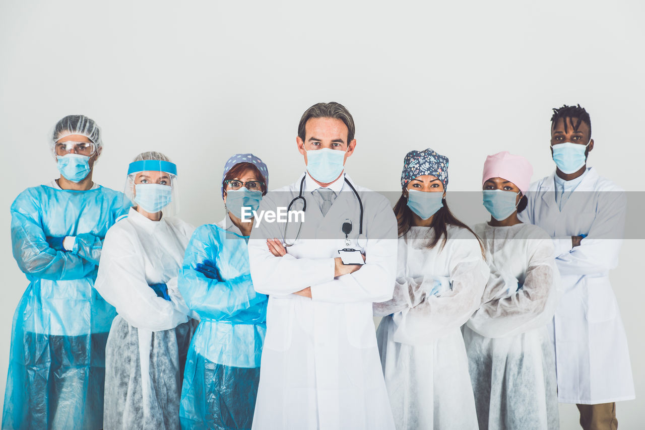 Portrait of doctors wearing mask standing against white background