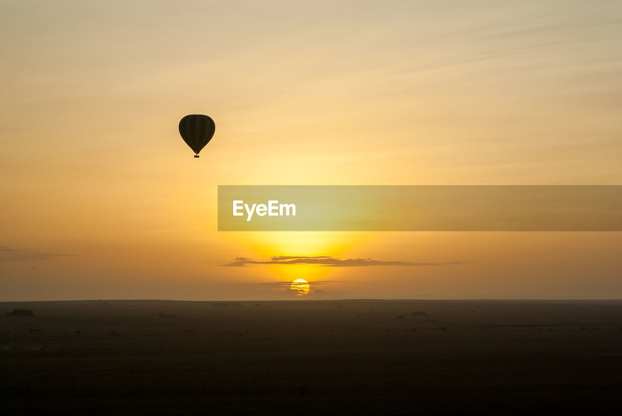 Hot air balloon flying against sky during sunset