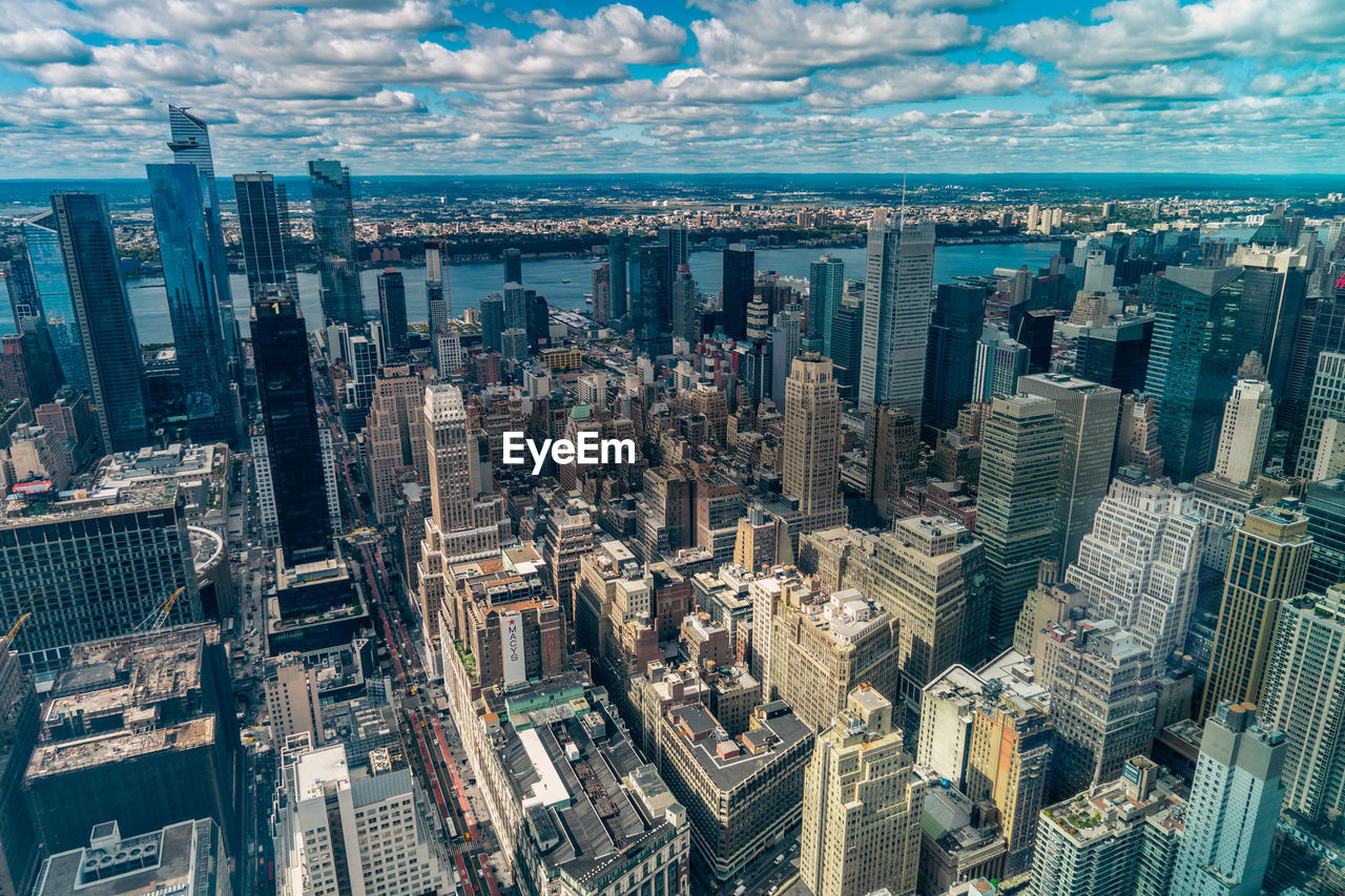 Aerial view of illuminated skyscraper buildings in city at day at high angle