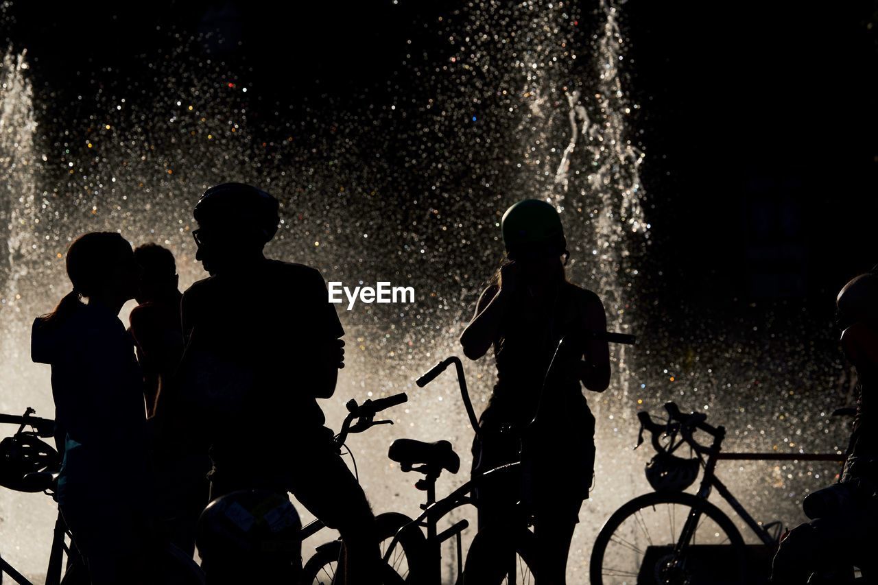 SILHOUETTE MEN WITH BICYCLE STANDING ON STREET AT NIGHT