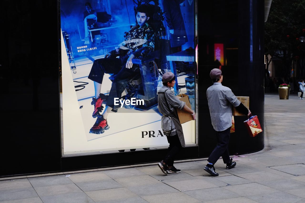 REAR VIEW OF PEOPLE WALKING ON CITY STREET