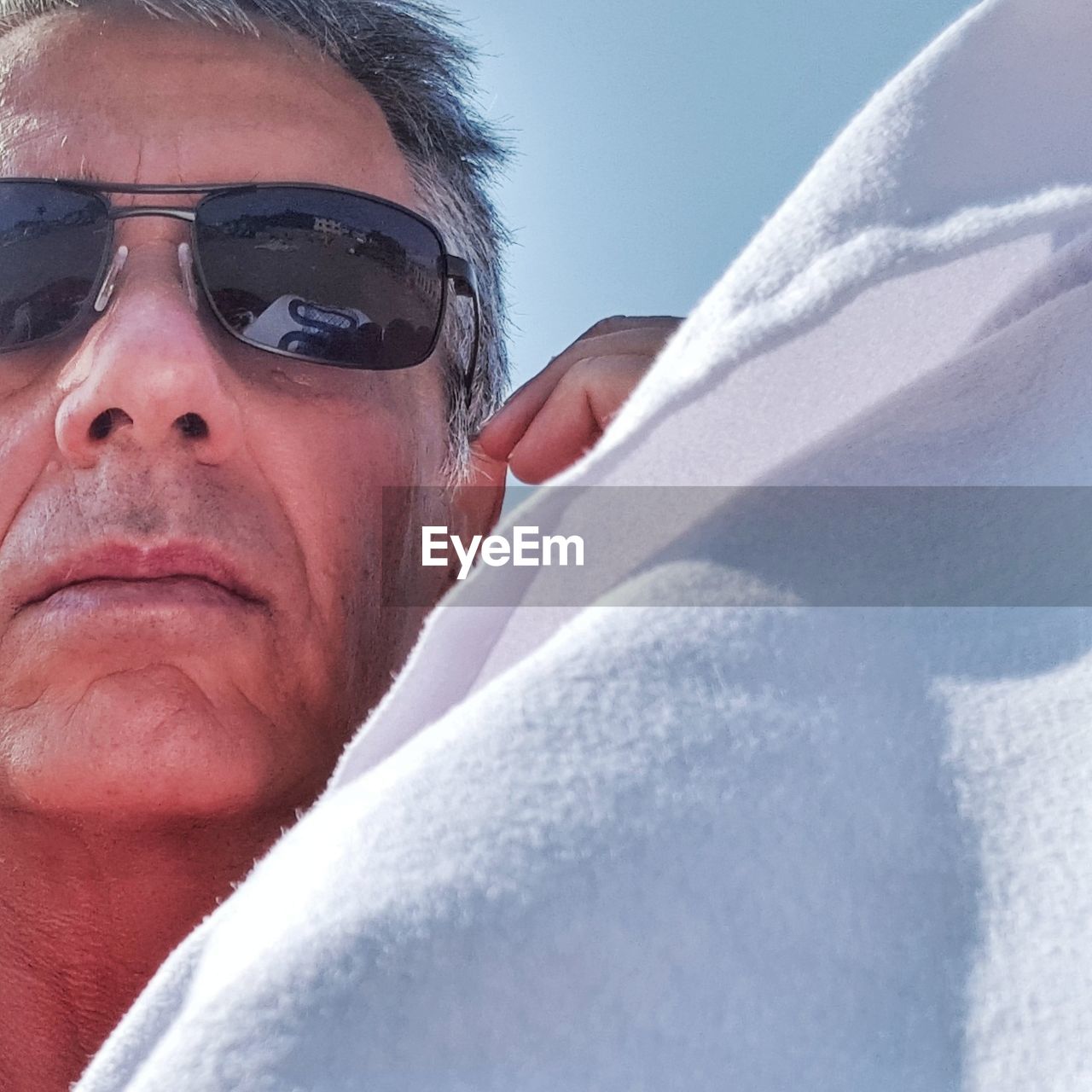 Close-up portrait of mature man wearing sunglasses against sky