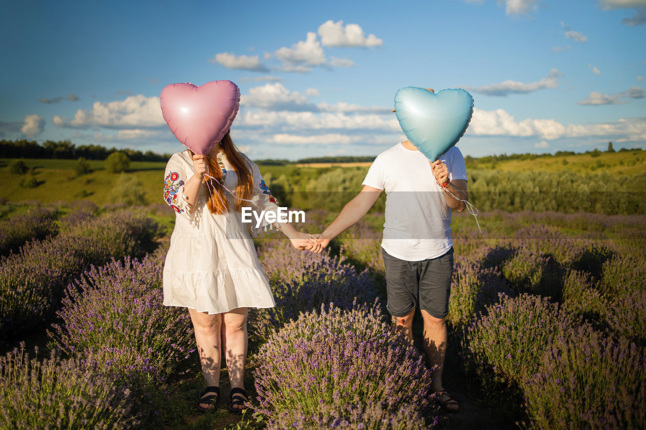 Couple holding balloons in field