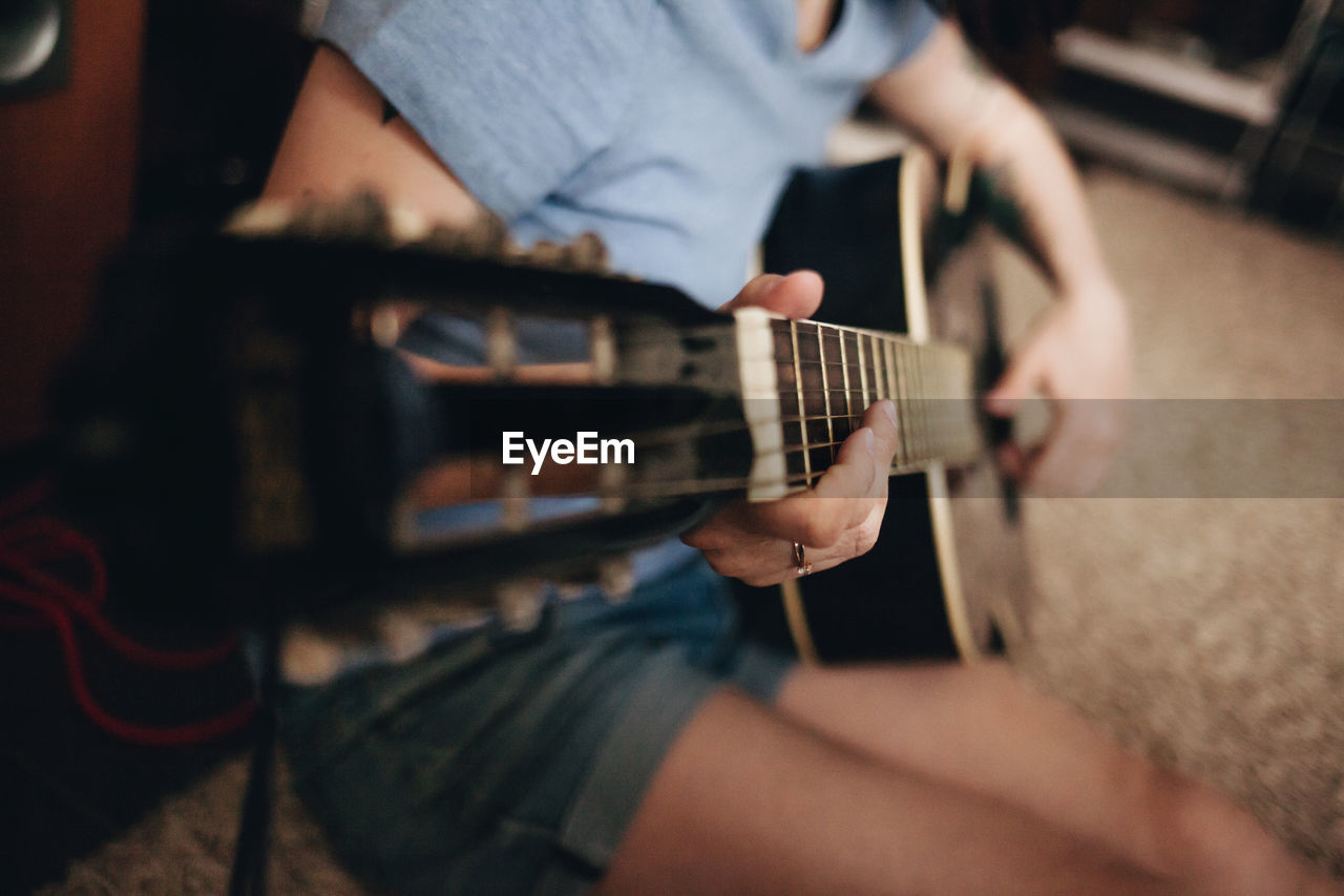 Midsection of woman playing guitar