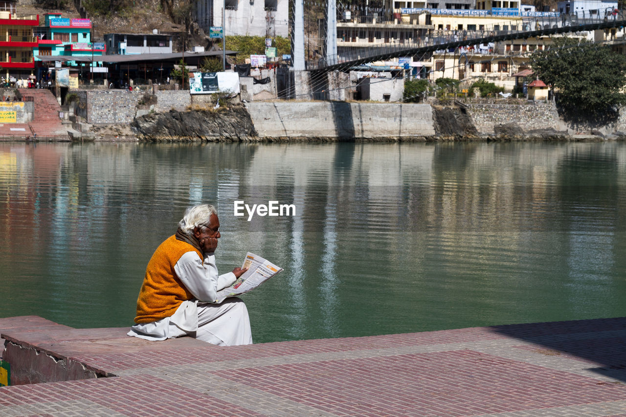 MAN SITTING ON RIVERBANK