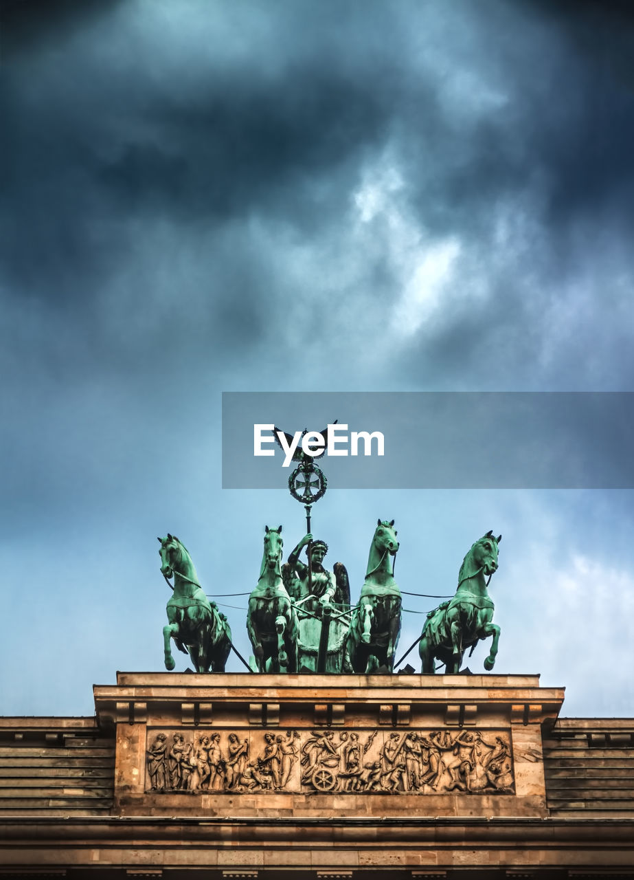 Low angle view of brandenburg gate against cloudy sky