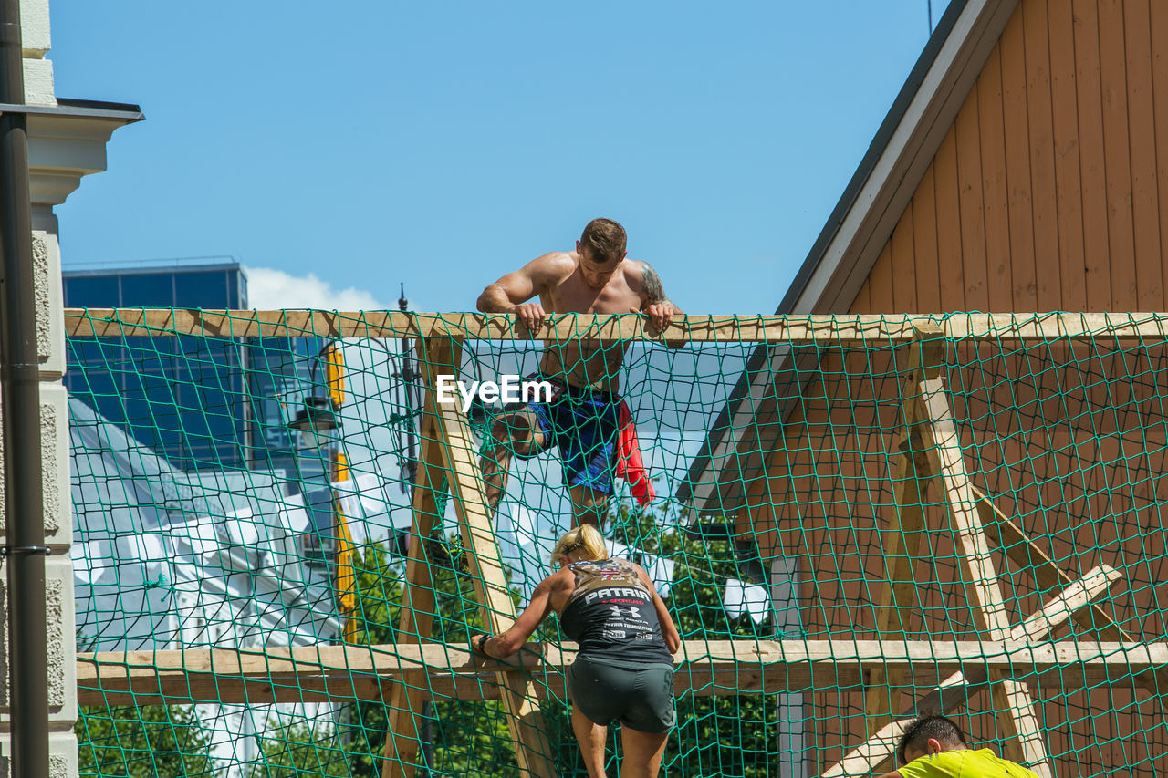 REAR VIEW OF SHIRTLESS MAN STANDING AGAINST SKY