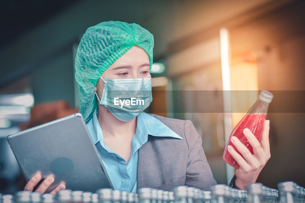 Woman using digital tablet while inspecting drinks in factory