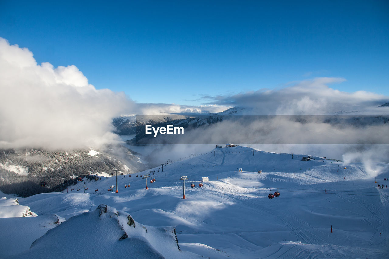Scenic view of ski lift over snowcapped mountain against sky