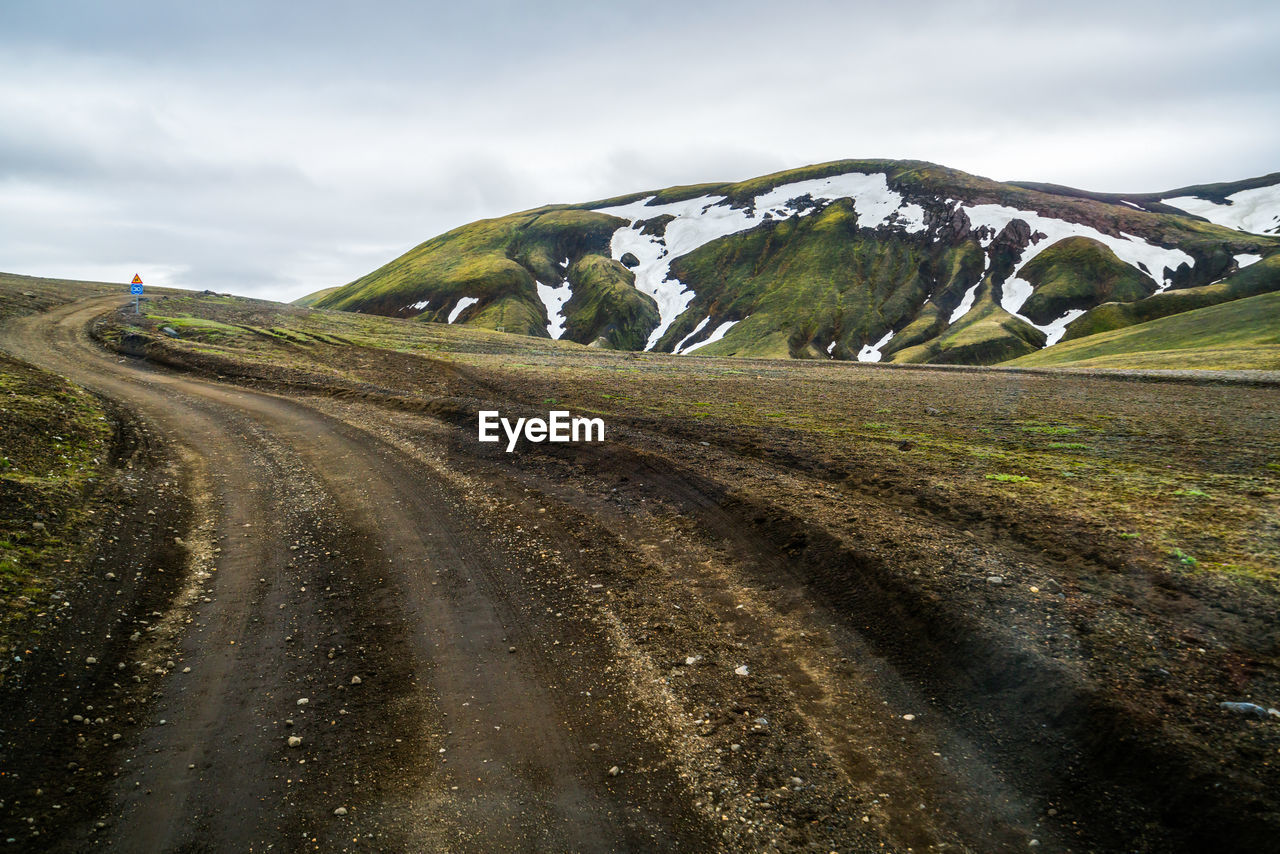 Road leading towards mountains against sky