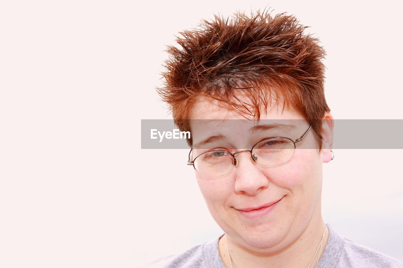 Close-up portrait of smiling mid adult lesbian woman against white background