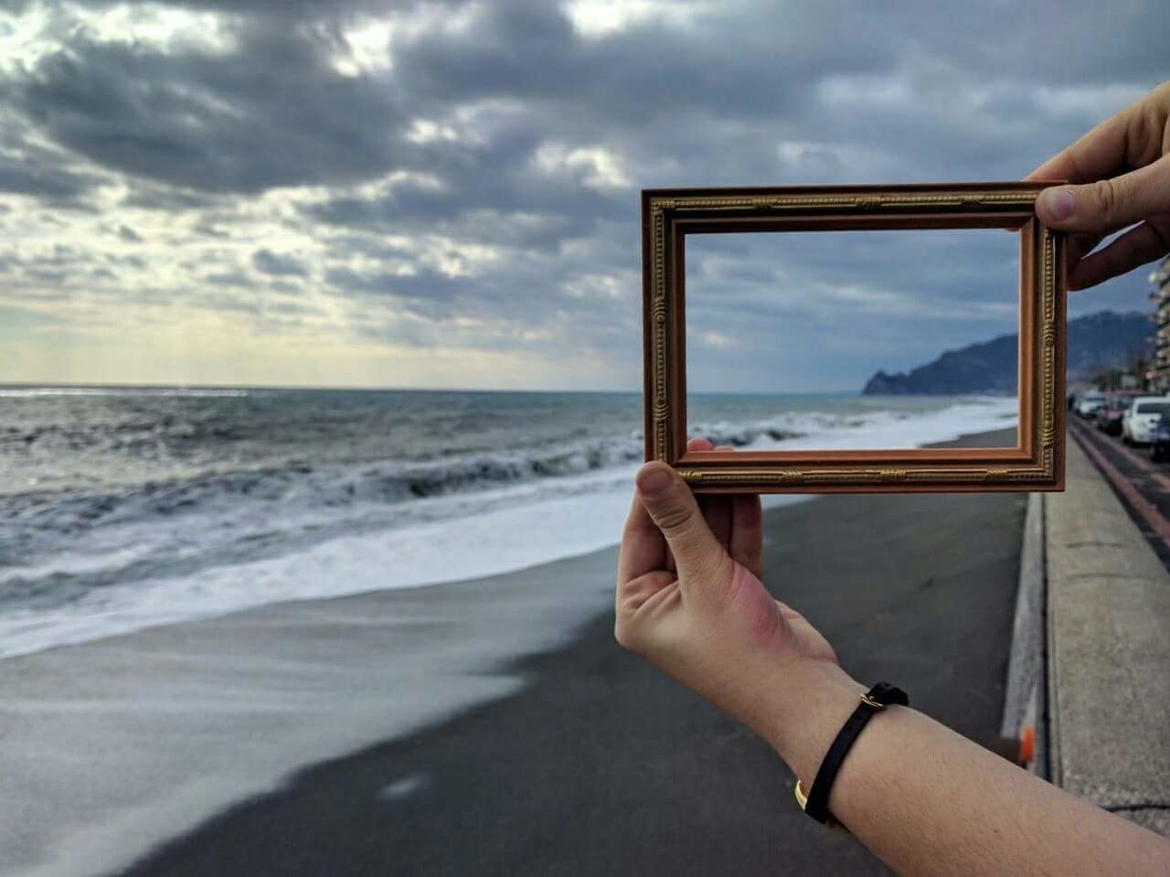 Cropped hand holding frame at beach