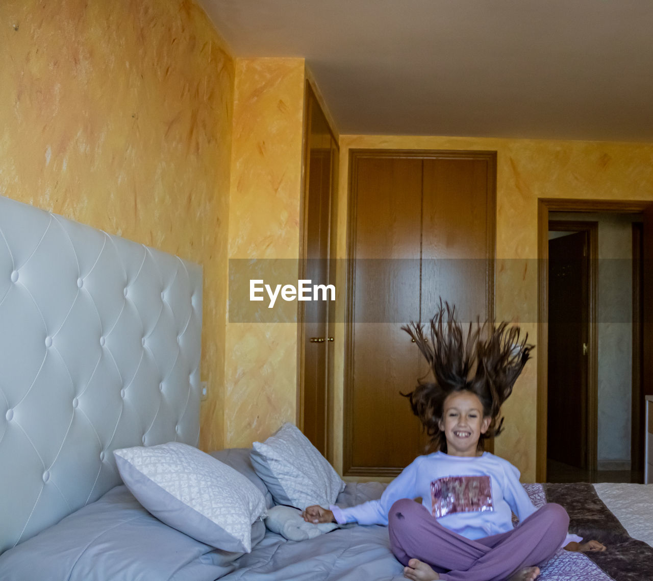 PORTRAIT OF GIRL SMILING IN BED AT HOME