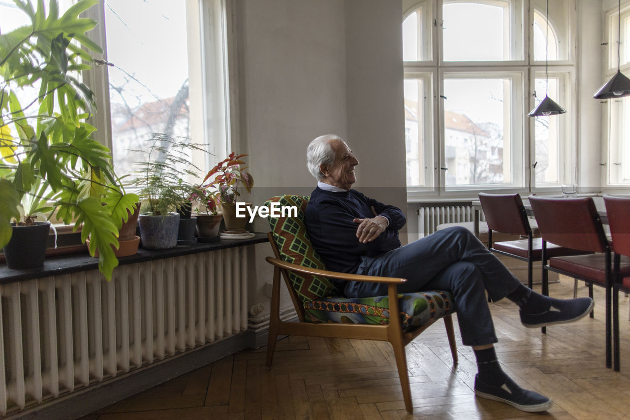 Happy senior man sitting on chair at home