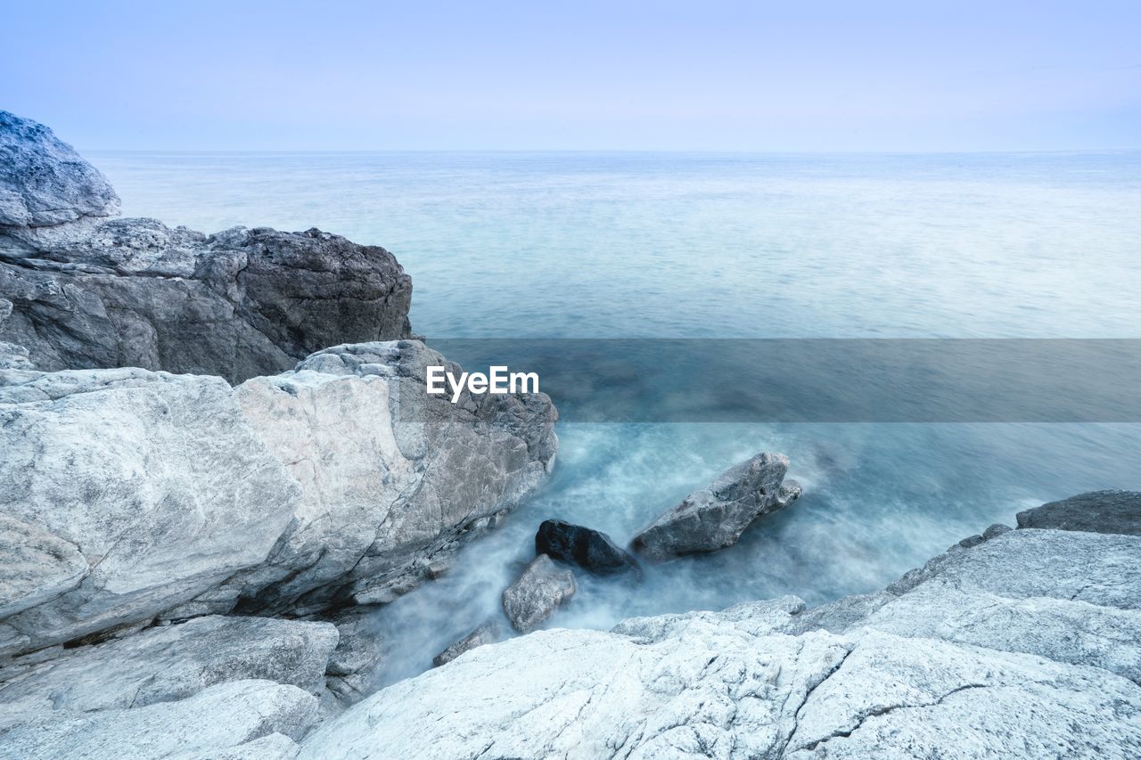 Scenic view of rocks in sea against blue sky