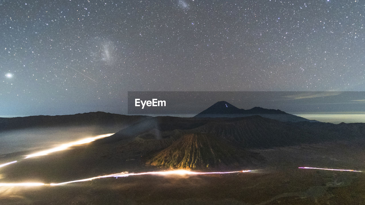 SCENIC VIEW OF ILLUMINATED MOUNTAINS AGAINST STAR FIELD