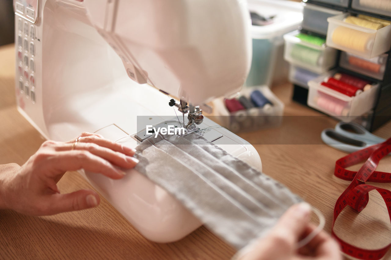 Woman hands using the sewing machine to sew the face mask