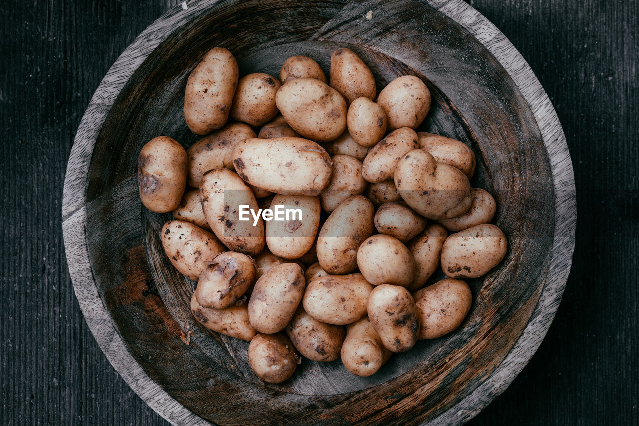 High angle view of raw potatoes in wooden bowl on table